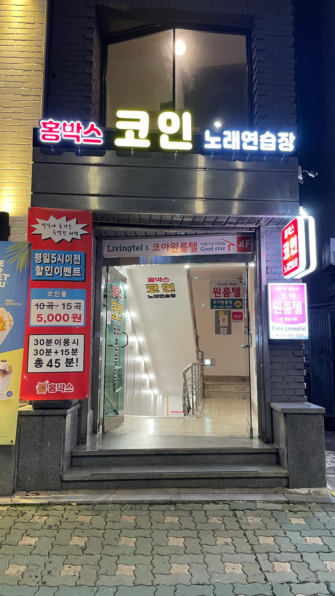 Nighttime entrance to HONGBOX coin karaoke in Hongdae, with illuminated Korean signage.